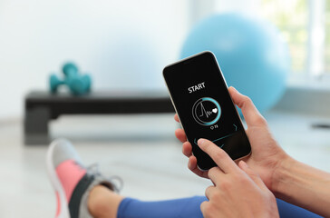 Wall Mural - Young woman using fitness app on smartphone indoors, closeup. Space for text
