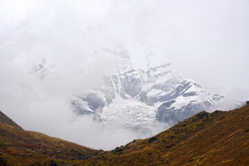 Closeup Mt. Machapuchare in the mist and fog is a mountain in the Annapurna Himalayas of north central Nepal seen from ABC , Nepal - trekking route Adventure Backpacking outdoor 