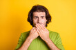 © deagreez - Photo of serious young man hands cover mouth look camera wear green t-shirt isolated yellow color background