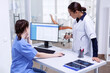 © DC Studio - Stomatolog and nurse in tooth clinic checking patient appointment looking at computer monitor. Stomatology assistant and teeth doctor discussing in reception of dental office