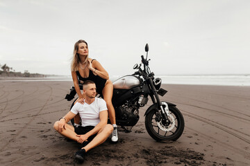 Wall Mural - Young couple riders together on sand beach by motorbike - travel concept