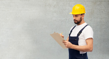 profession, construction and building concept - male worker or builder in helmet with clipboard over grey concrete background