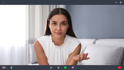 Wall Mural - Woman communicating with coworkers from home using video chat, view through camera