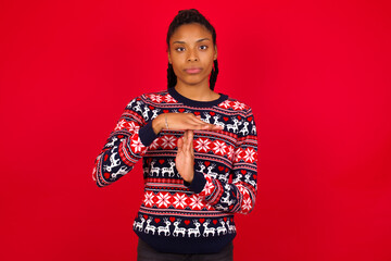Wall Mural - Young beautiful African American woman standing against red background being upset showing a timeout gesture, needs stop, asks time for rest after hard work, demonstrates break hand sign