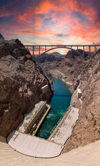 Wall Mural - vertical shot of a water canal with the hoover dam in the background during sunset