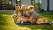 © Gorodenkoff - Portrait of Father, Mother, and Son Having Picnic on the Lawn, Posing with Happy Golden Retriever Dog. Idyllic Family Have Fun with Loyal Pedigree Doggy Outdoors in Summer House Backyard.