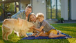 © Gorodenkoff - Portrait of Father, Mother and Son Having Picnic on the Lawn, Posing with Happy Golden Retriever Dog. Idyllic Family Have Fun with Loyal Pedigree Dog Outdoors in Summer House Backyard.