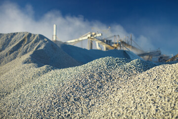 Huge hills of crushed stone against the background of mining industry facilities, close-up.