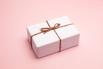 Wall Mural - Gift box wrapped in white paper on pastel pink background