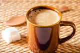 Taza de arcilla con café caliente sobre fondo rústico
