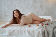© Tatiana Timofeeva/Stocksy - portrait of an Asian woman curve model in a swimsuit sitting on a bed
