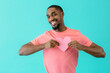 © Carlos David - Portrait of a smiling young man holding tight pink cutout heart for valentineÕs day