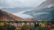 A view of the Glenfinnan viaduct train bridge in Scotland with foggy mountains behind it