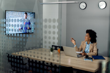 Wall Mural - Happy blck businesswoman talking while having online meeting with corporate manager from the office.