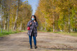 © TheVisualsYouNeed - new normal Autumn walk outdoors - young happy and pretty Asian Japanese woman in face mask walking cheerful at beautiful city park in vibrant yellow and orange tree leaves