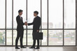 © nikomsolftwaer - Negotiating business,Image of businesswomen Handshaking. young asuan businessmen shaking hands together while standing by windows in an office