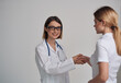 © SHOTPRIME STUDIO - doctor and patient shaking hands on a light background stethoscope around the neck