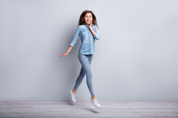 Wall Mural - full size profile photo of impressed shy girl jumping wear shirt jeans sneakers isolated on concrete