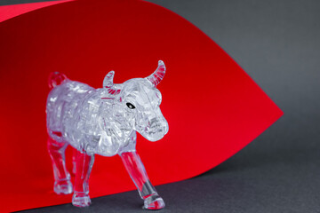 Wall Mural - Figurine of a bull from three dimensional puzzles on red and gray background. Symbol of coming New Year 2021, business, stock exchange, finance.