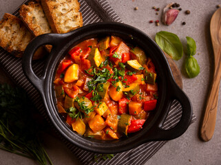 Cooked various chopped vegetables with herbs in a black cooking pot