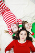 © alexkich - A family in striped pajamas is resting at home. Little children dressed as elves are lying on the sofa. Happy family.