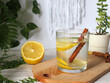 Glass of lemonade with lemon, drink with cinnamon stick on a wooden board
