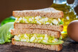 Sandwich with avocado and egg on wooden background