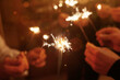 © Song_about_summer - group of friends with sparklers celebrating Christmas, hands holding sparkling lights
