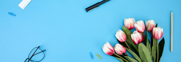 Poster - View of tulips, eyeglasses, pens, ruler, and paper clips with copy space isolated on a blue surface