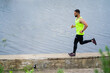 © Georgii - Athletic jogging man in stylish sportswear on workout outside in front of water