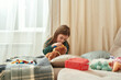 © Svitlana - A cute small girl playing an ENT doctor checking her teddybear's ears while sitting on a sofa in a well-lighted room