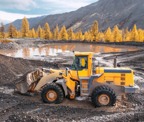 Wall Mural - Wheel loader at work. It transports gold-bearing mountain soil to the hopper of the washing device. The gold mining industry in Eastern Siberia widely uses such equipment as front loader, bulldozer, 