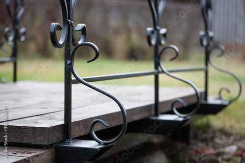Fotografía Garden bridge with black wrought iron balusters against the background of a gree