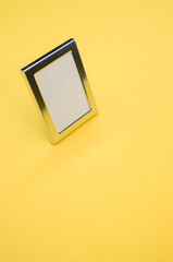 Wall Mural - Closeup shot of a chrome picture frame isolated on a yellow background