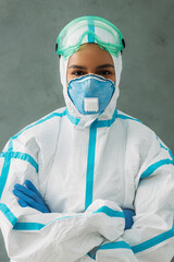 Wall Mural - Female nurse wearing protective medical suit standing with arms crossed and looking at camera