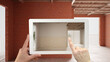 Augmented reality concept. Hand holding tablet with AR application used to simulate furniture and design products in an interior construction site, empty interior with ceramic tiles