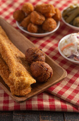 Wall Mural - Breaded and Fried Fillets of Fish with Hushpuppies on a Wooden Table