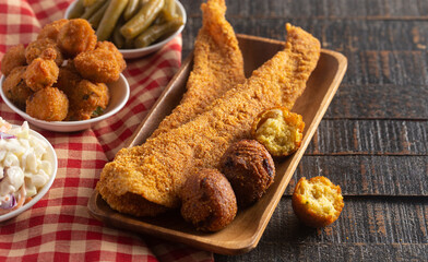 Wall Mural - Breaded and Fried Fillets of Fish with Hushpuppies on a Wooden Table