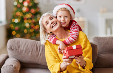 Wall Mural - Cheerful child congratulating grandmother at Christmas