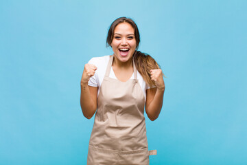 young hispanic woman feeling shocked, excited and happy, laughing and celebrating success, saying wow!