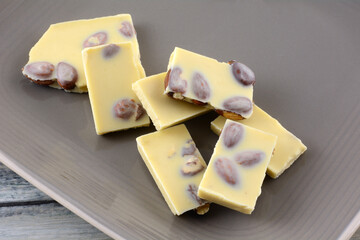 Wall Mural - Almond white chocolate candy bar pieces with whole almond nuts on brown plate