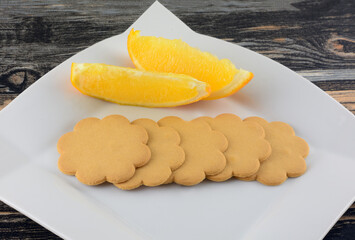 Wall Mural - Orange and vanilla cookie biscuits with two orange slices on white snack plate