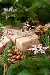 Gift boxes in craft paper. Christmas background. Christmas gifts under spruce branches on a brown wooden background