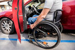 © romaset - Young handicapped driver getting in red car fom wheelchair