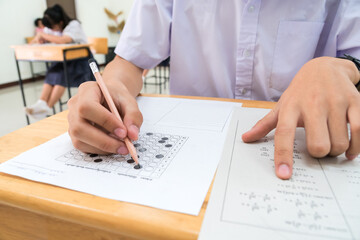 Wall Mural - Students Asian undergraduate testing of mathematics solution examination in room sitting serious on row chair doing final exams in classroom with Thailand uniform