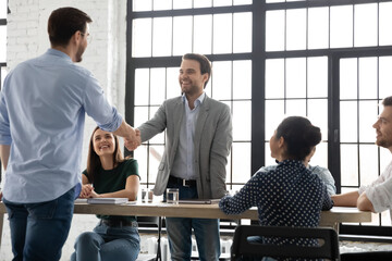 Congratulate you on promotion. Male leader ceo boss handshaking with happy young man worker greeting with financial reward, salary or career growth, appreciating for good job, welcoming new teammate