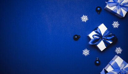 Gift boxes cyan. White gifts with cyan ribbon, New Year balls and winter tree in Christmas composition on dark blue background for greeting card. Xmas backdrop with space for text.