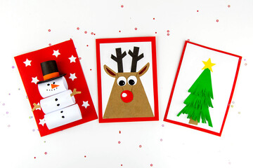 DIY Christmas cards kids. Three cards with a Christmas tree, a deer, a snowman from colored paper.