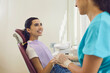 Dental specialist holding hand of happy woman sitting in chair at the dentist's office