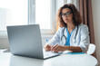 © Stock 4 You - Hispanic latin female doctor make online video call consult patient on laptop. Medical assistant young woman therapist videoconferencing to web camera. Telemedicine concept. Online doctor appointment.
